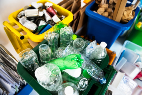 Tempat sampah daur ulang berisi botol plastik, kaleng, dan kertas